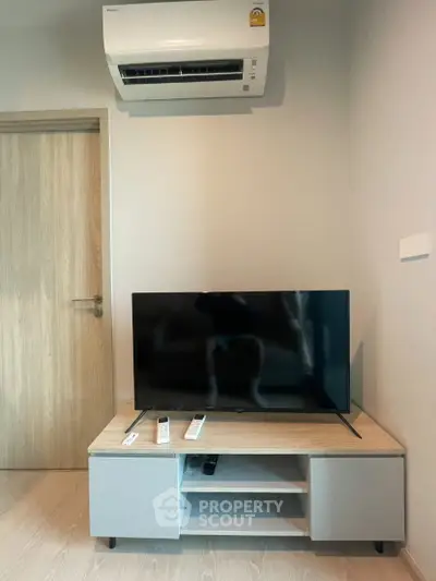 Modern living room with sleek TV setup and air conditioning unit, perfect for comfortable living.