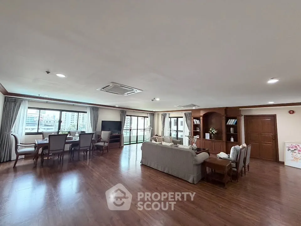 Spacious living room with elegant dining area and large windows offering city views.