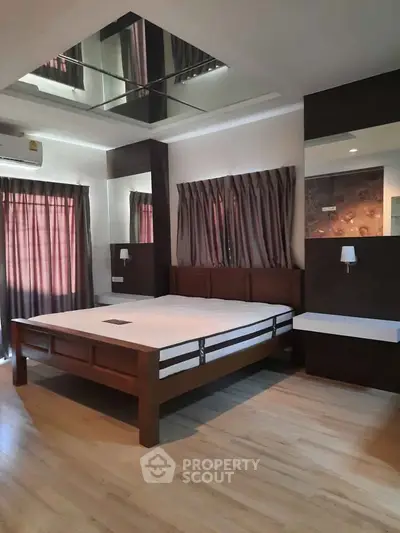 Spacious bedroom with modern design and wooden flooring, featuring large windows and elegant lighting.