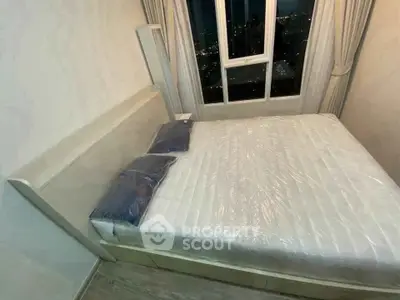Cozy bedroom with large window offering stunning city views, featuring a comfortable bed and elegant curtains.