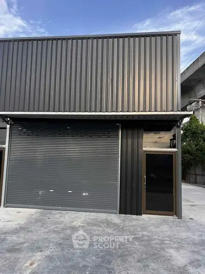 Modern industrial warehouse with sleek metal facade and large roller door.