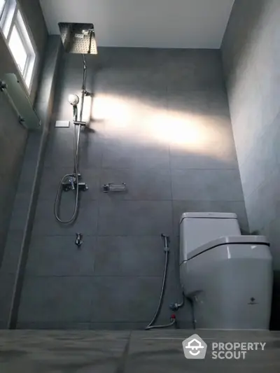 Modern bathroom with sleek gray tiles and a luxurious rainfall showerhead, offering a serene and stylish personal spa experience.