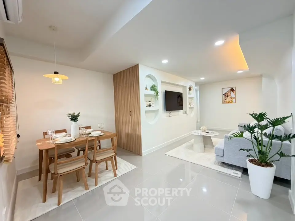 Modern living room with dining area, featuring sleek furniture and elegant decor.