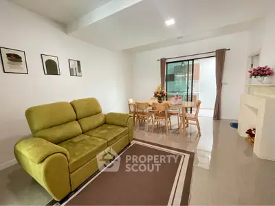 Spacious living room with green sofa and dining area, perfect for family gatherings.