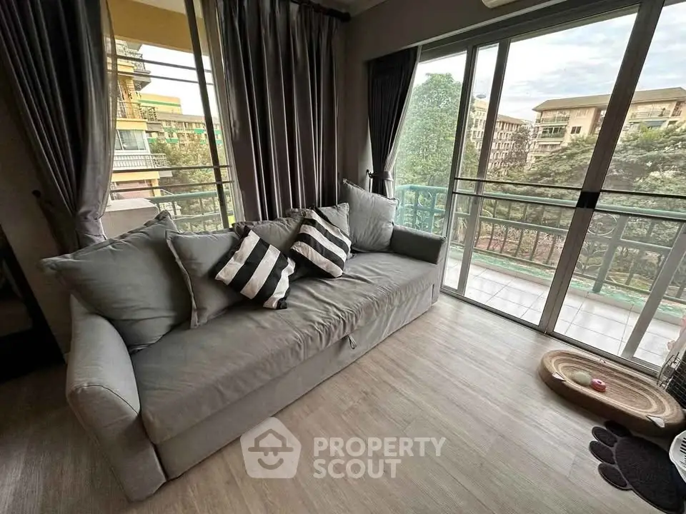 Cozy living room with a large sofa and balcony view, perfect for relaxation.