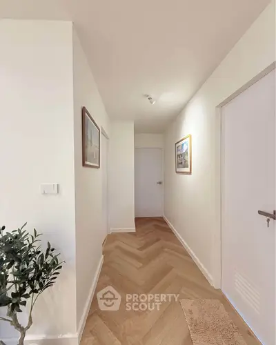 Bright hallway with wooden herringbone flooring and framed art on walls