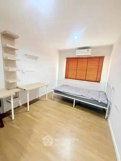 Minimalist bedroom with wooden flooring and natural light