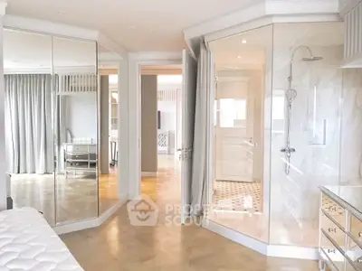 Luxurious bedroom with mirrored closets and elegant ensuite bathroom featuring a glass shower.