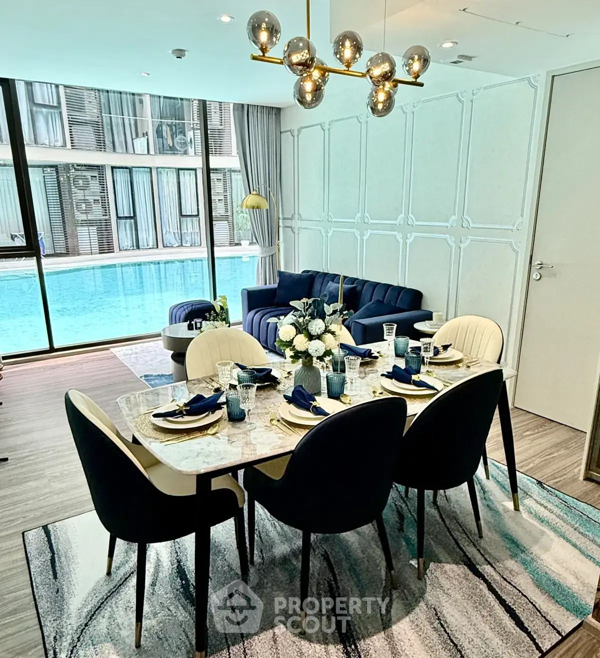 Luxurious living room with pool view, elegant dining setup, and modern decor in a high-end apartment.