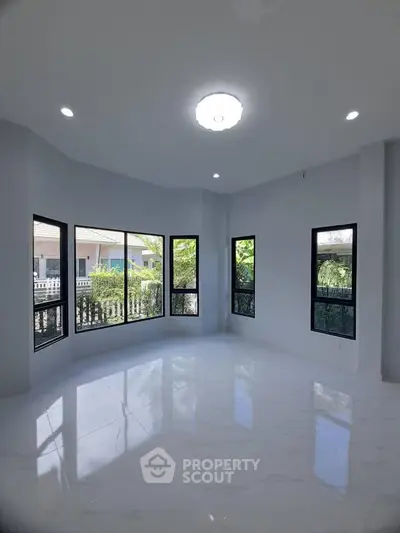 Spacious bright room with large windows and modern lighting in a contemporary home.