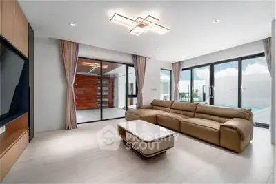 Spacious modern living room with elegant sofa and large windows offering natural light.