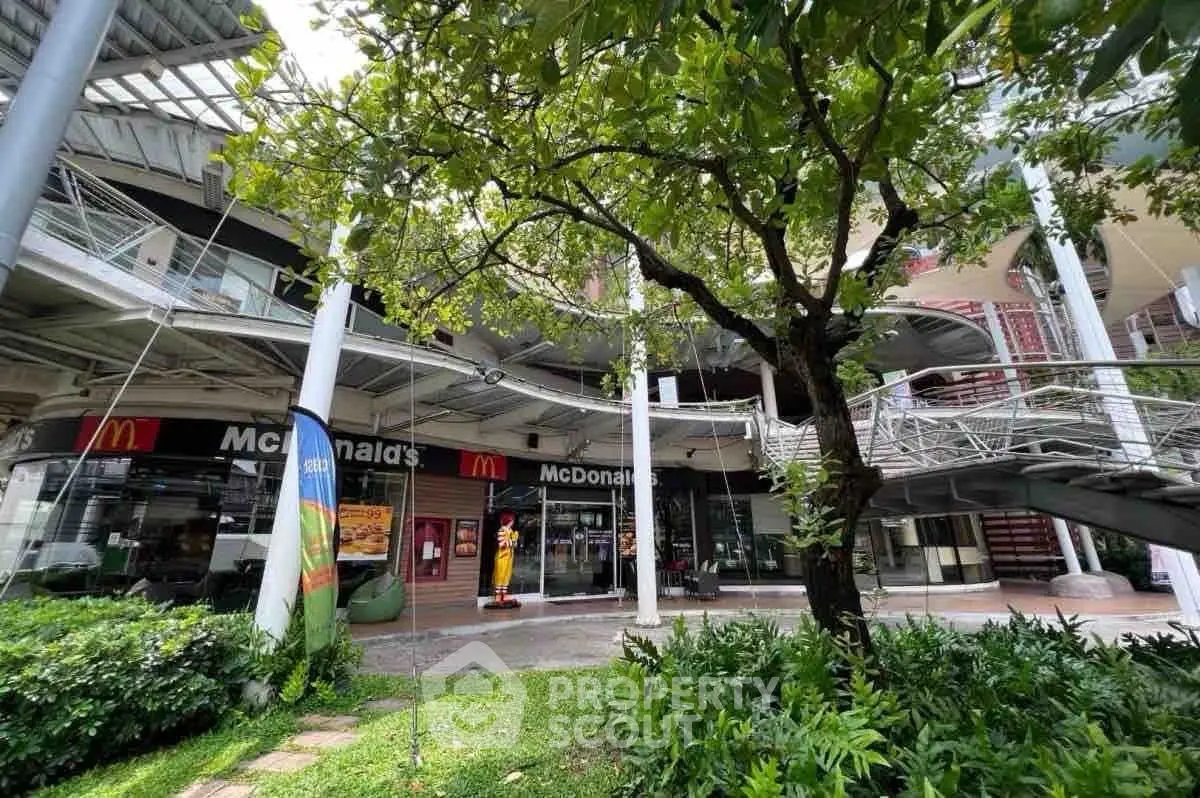 Modern commercial building exterior with lush greenery and iconic fast-food restaurant