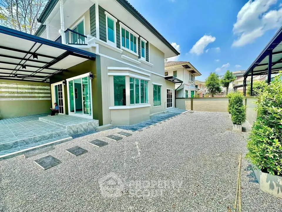 Spacious modern house exterior with large driveway and garden area under clear blue sky.
