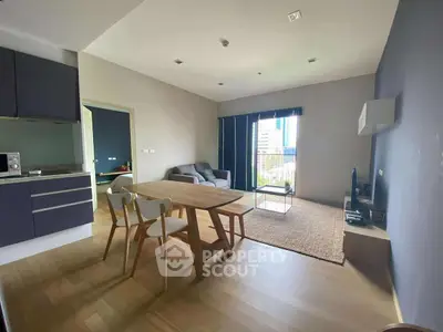 Modern open-layout living room with kitchen, featuring sleek furniture and a city view.