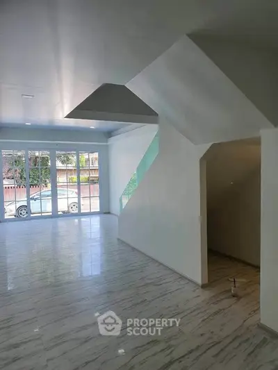 Spacious modern living room with large windows and sleek marble flooring