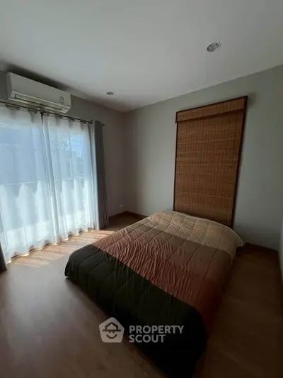 Cozy bedroom with natural light and modern decor, featuring a comfortable bed and air conditioning.