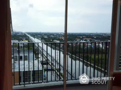 Stunning high-rise balcony view overlooking a serene river and cityscape, perfect for urban living.