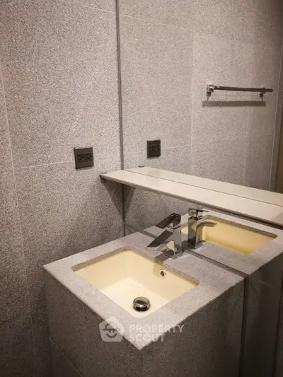 Modern bathroom with sleek sink and mirror, featuring minimalist design and neutral tones.