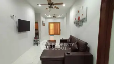 Spacious living room with modern decor and ceiling fans, perfect for relaxation and entertainment.