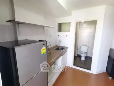 Compact kitchen with fridge and adjacent bathroom in modern apartment