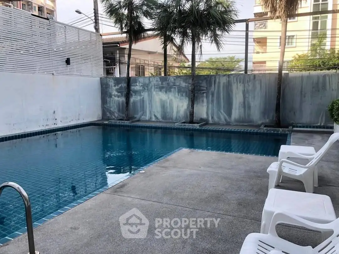 Inviting outdoor pool area with lounge chairs and privacy fencing, perfect for relaxation.