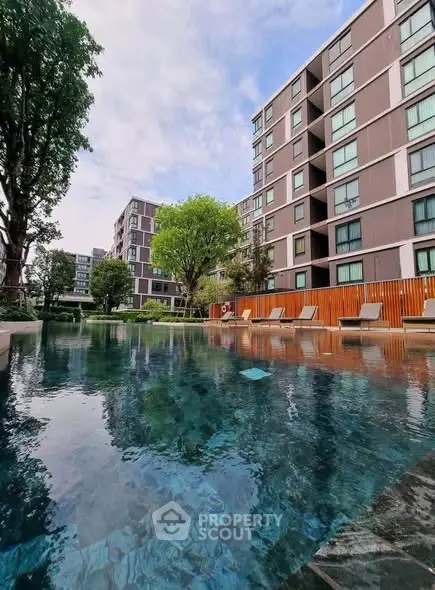 Modern apartment complex with a serene pool and lush greenery