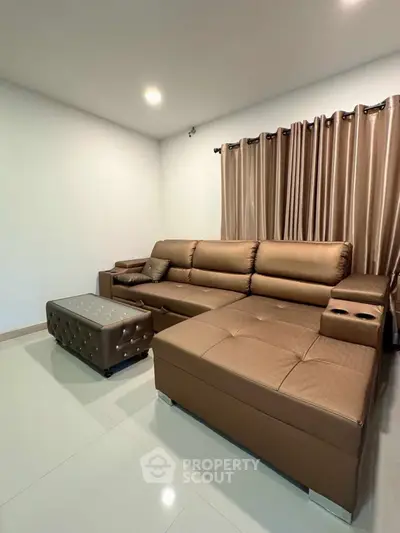Modern living room with stylish brown leather sectional sofa and elegant curtains.