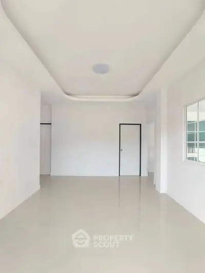 Spacious empty room with modern ceiling design and large window, perfect for customization.