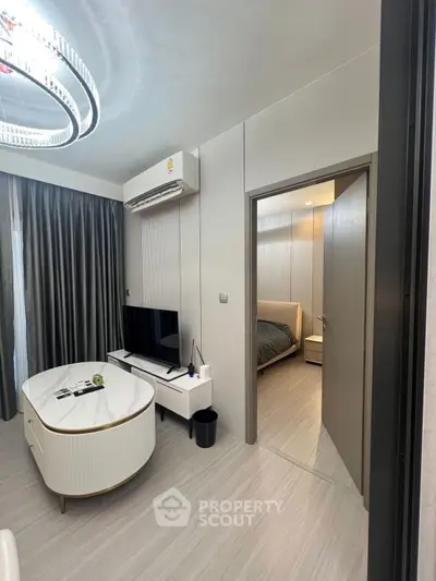 Modern living room with sleek furniture and view into cozy bedroom