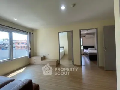 Spacious living area with large windows and two bedrooms, featuring modern wooden flooring.