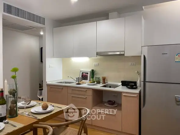 Modern kitchen with dining area, featuring sleek cabinetry and stainless steel appliances.