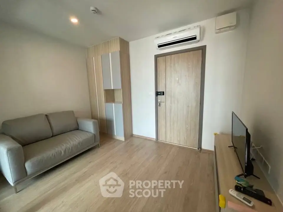 Modern living room with sleek design, featuring a comfortable sofa and wall-mounted air conditioning unit.