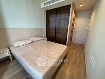 Modern bedroom with wooden flooring and built-in wardrobe in a stylish apartment.