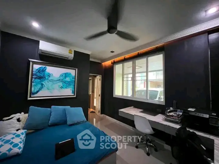 Modern bedroom with stylish decor and large window, featuring a comfortable bed and sleek workspace.