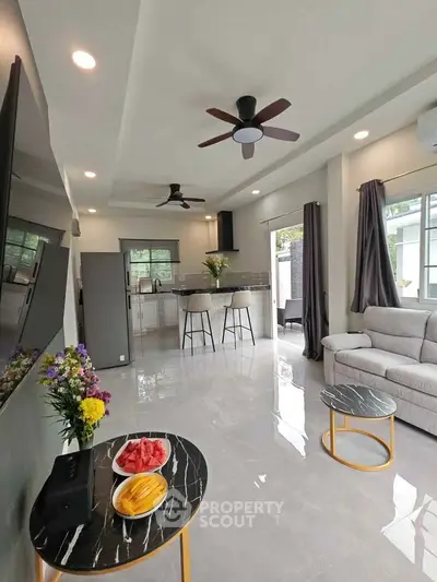 Spacious modern living room with open kitchen, stylish decor, and natural light.