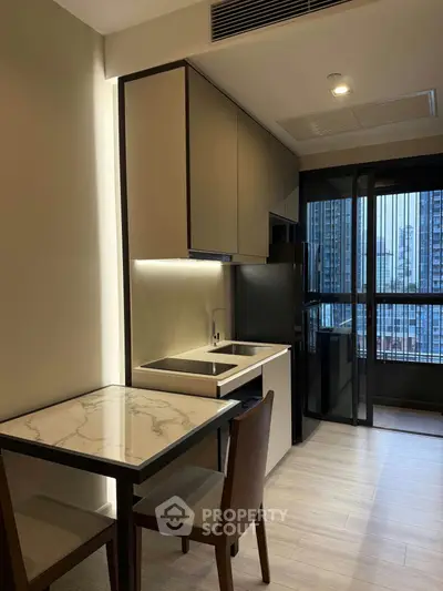 Modern kitchen with sleek cabinetry and city view from window, featuring a compact dining area.