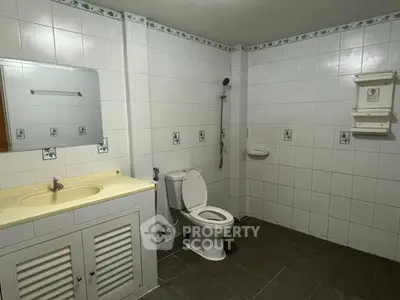 Spacious bathroom with white tiles and modern fixtures.
