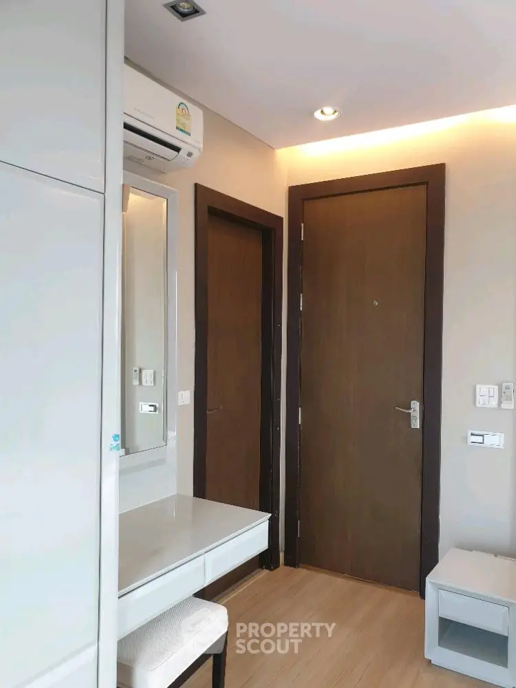 Modern interior with wooden doors, air conditioning, and a sleek vanity in a compact space.