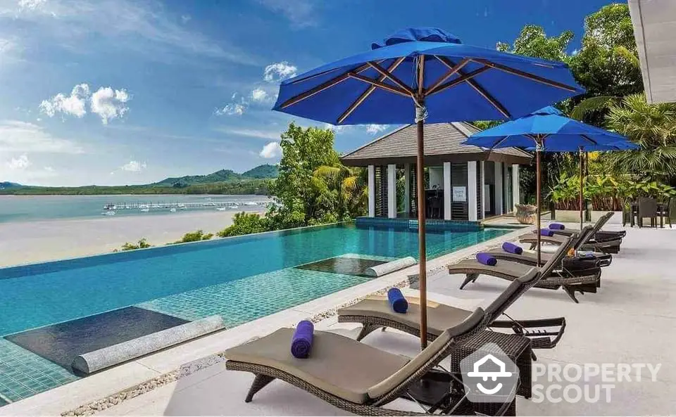 Luxurious infinity pool with stunning ocean view and sun loungers in tropical paradise.