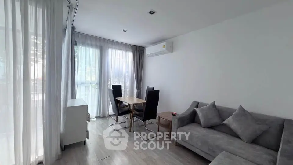 Modern living room with sleek furniture and natural light, featuring a cozy sofa and dining area.