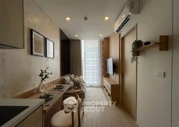Modern living room with stylish decor and natural light, featuring a cozy dining area and wall-mounted TV.