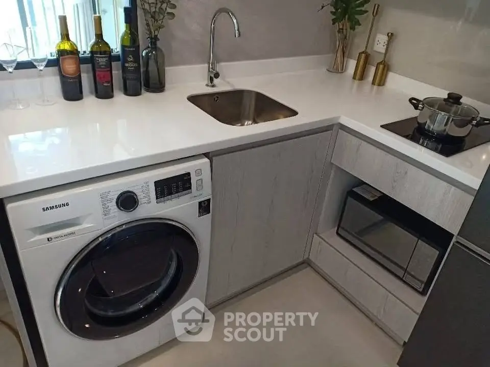 Modern kitchen with sleek appliances and stylish decor, featuring a washing machine and compact layout.