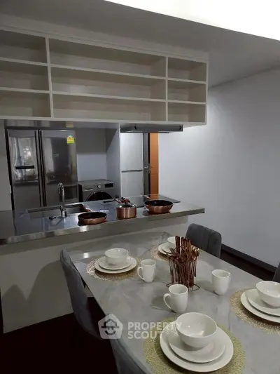 Modern kitchen with dining area, featuring stainless steel appliances and elegant table setting.
