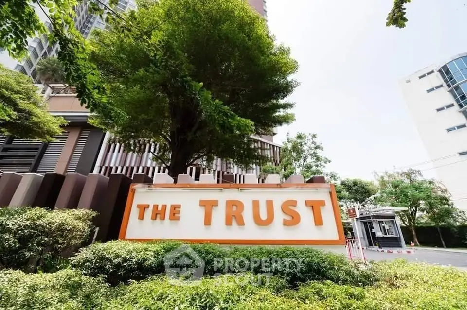 Modern building entrance with lush greenery and prominent signage at The Trust.