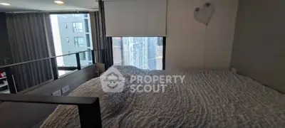 Cozy bedroom with large window offering city view in modern apartment