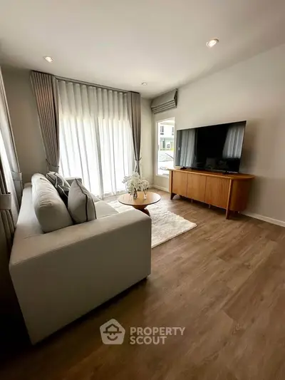 Stylish living room with modern decor, large TV, and elegant curtains, perfect for relaxation and entertainment.