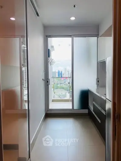 Modern kitchen with sleek cabinetry and city view from balcony.
