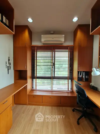 Spacious study room with built-in wooden shelves and large window view
