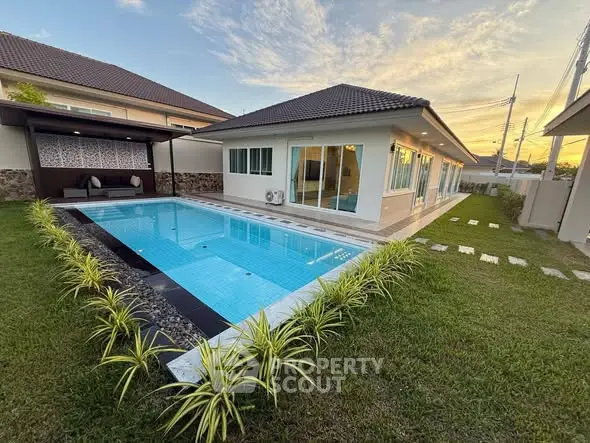 Stunning modern home with private pool and lush garden at sunset, perfect for luxury living.