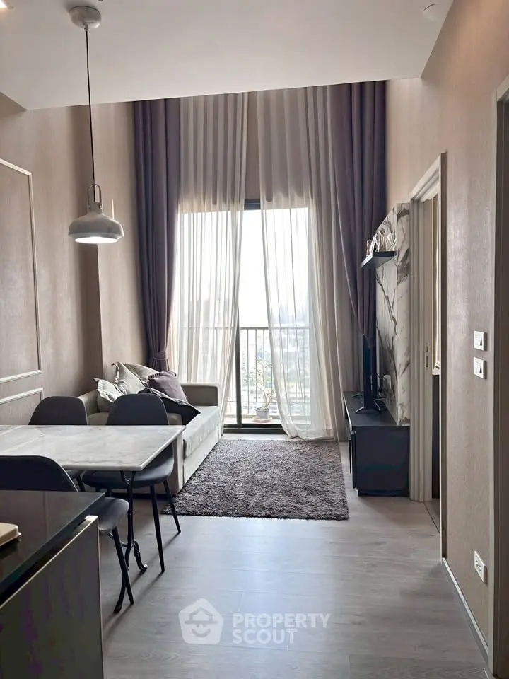 Modern living room with high ceilings and large window offering city views, featuring stylish decor and dining area.